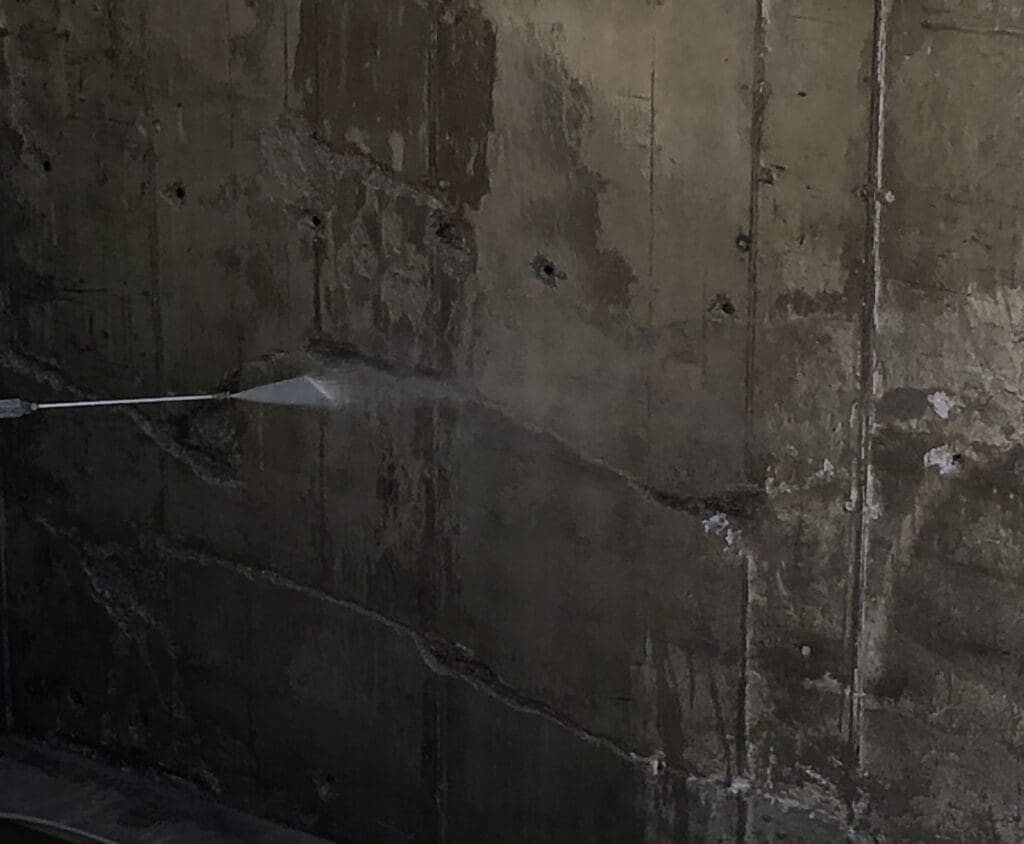 Струмінь води під високим тиском очищає бетонну поверхню стіни паркінгу